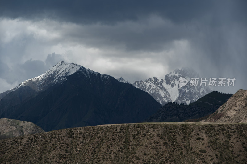 乌云下的雪山与多彩山峦风景