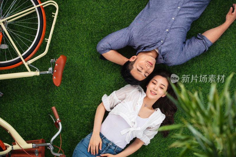甜蜜的青年伴侣躺在草地上