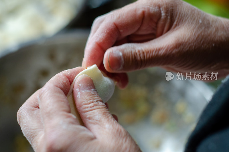 正在包饺子的母亲的手部特写