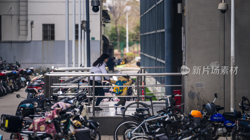 女子带小孩走过停放众多车辆的过道