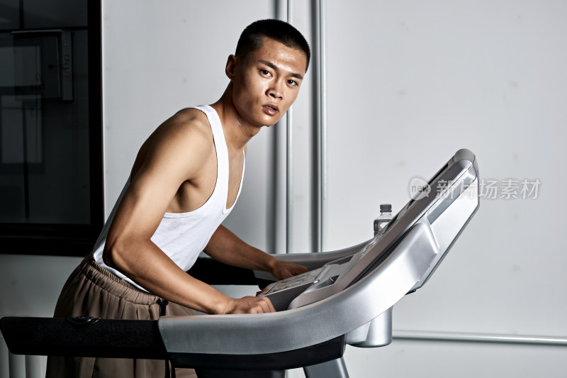 在室内用跑步机进行锻炼的亚洲健身男士形象