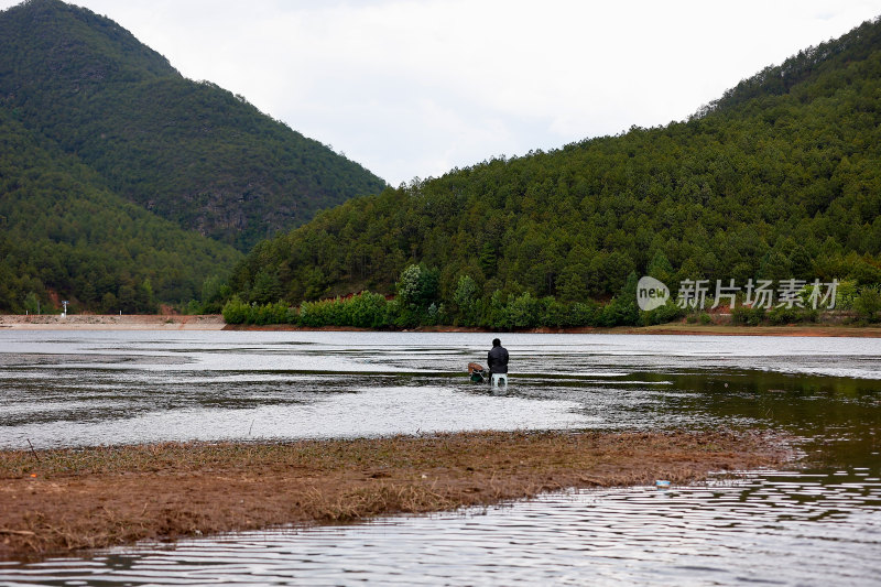 湖边小屋旁的人垂钓场景