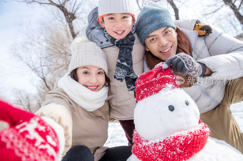 一家三口在雪地里堆雪人