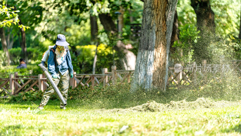 公园里的绿化工人正使用吹草机吹草地