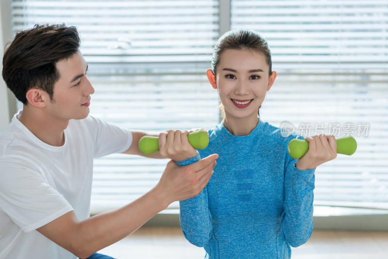 年轻女子在私教的指导下健身