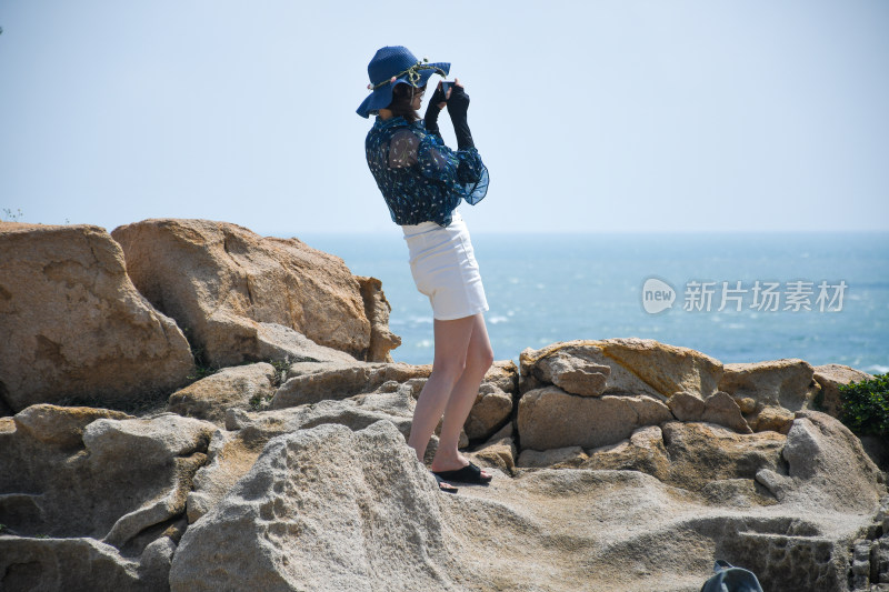 女子海边岩石上拍照