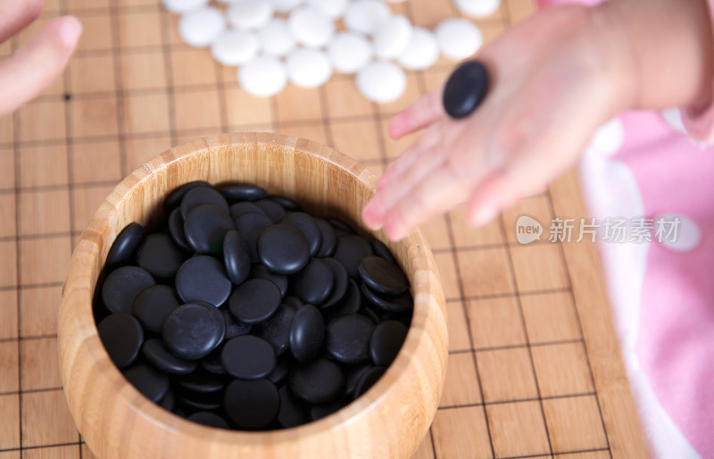 一只小手正把棋子放入棋盒中