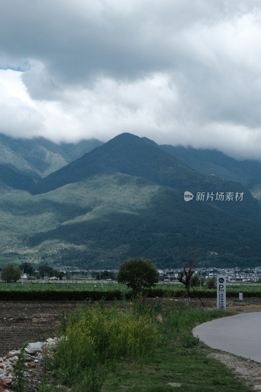 阴云下的青山远景及山脚下的土地