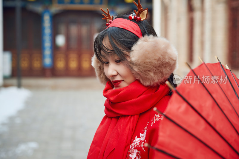 雪后在老城古巷穿着喜庆服饰的亚洲少女