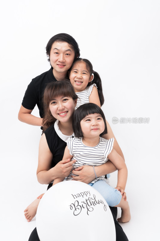 年轻的夫妻和两个女儿站在白色背景前