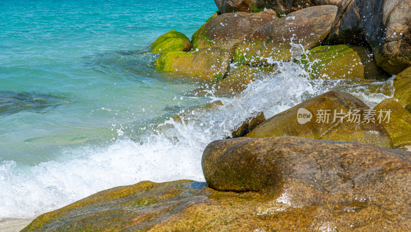 阳光下的海南三亚海岸线上礁石沙滩海浪浪花