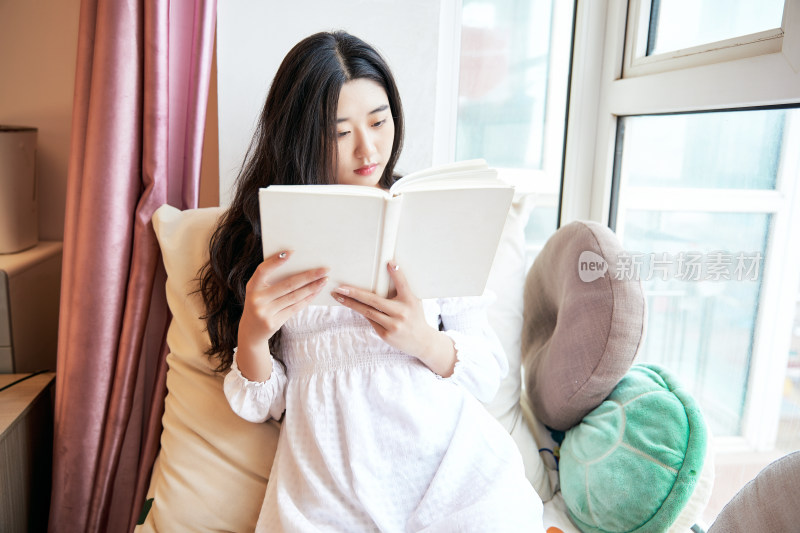 躺在舒适的飘窗上看书的女孩