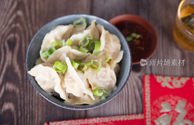 桌子上一碗饺子和蘸料红包及茶水