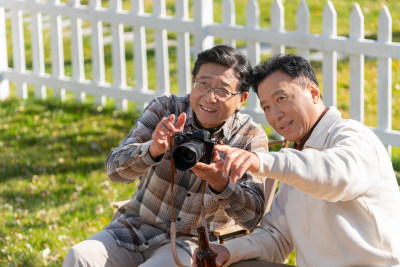 两个老年男人坐在露营地看数码相机