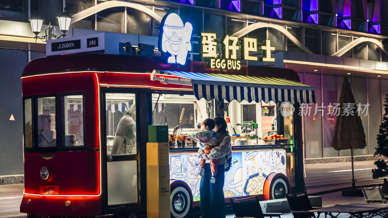 夜晚街头蛋仔巴士前的亲子场景