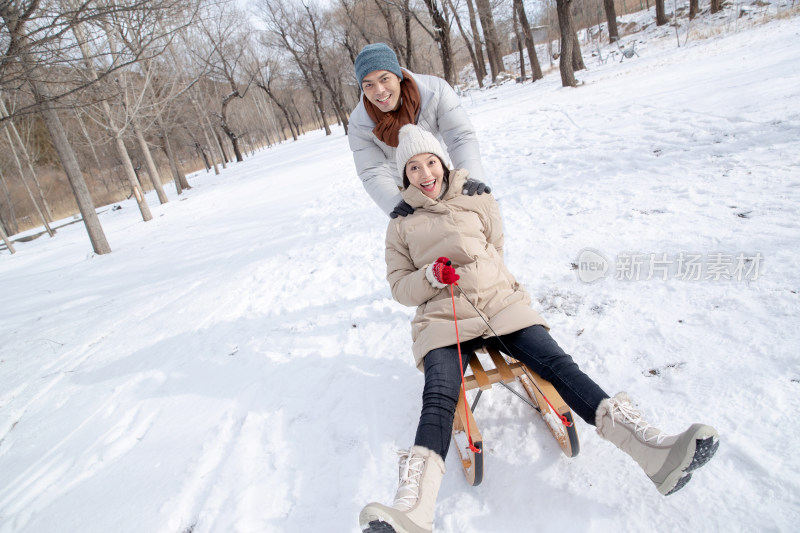 青年夫妇在雪地上玩雪橇