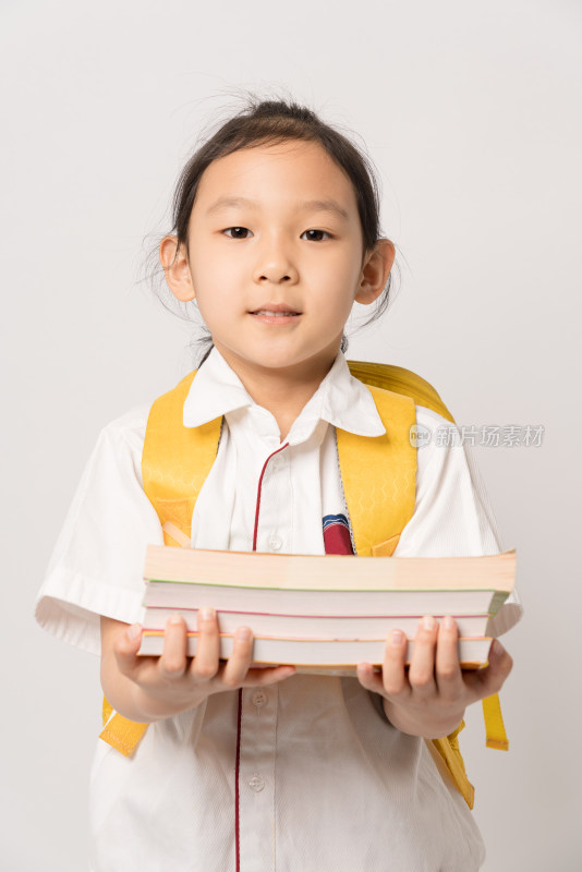 白色背景前怀抱书籍的中国女孩