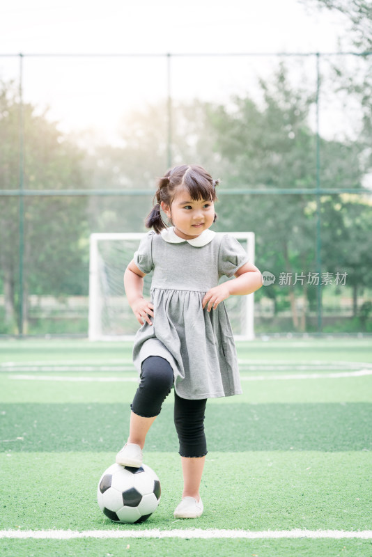 在足球场踢足球的中国女童