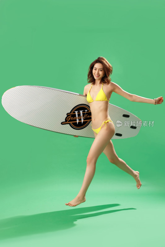 快乐的青年女人抱着冲浪板