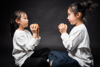 两个在黑背景前玩耍的亚裔女孩