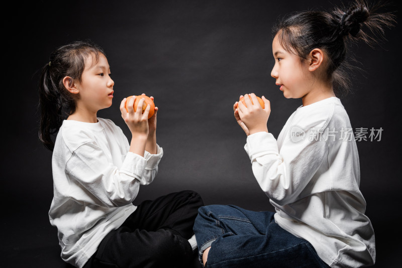 两个在黑背景前玩耍的亚裔女孩