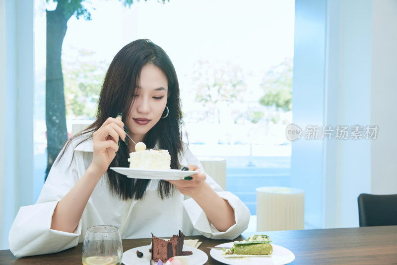 在烘焙店吃蛋糕喝饮料的可爱亚洲少女