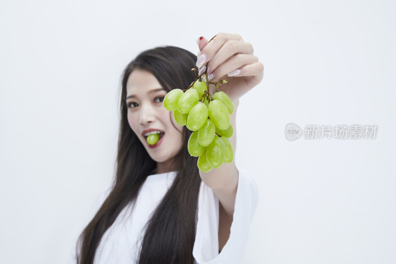 吃葡萄的穿白色长T血衫的长发可爱少女人像