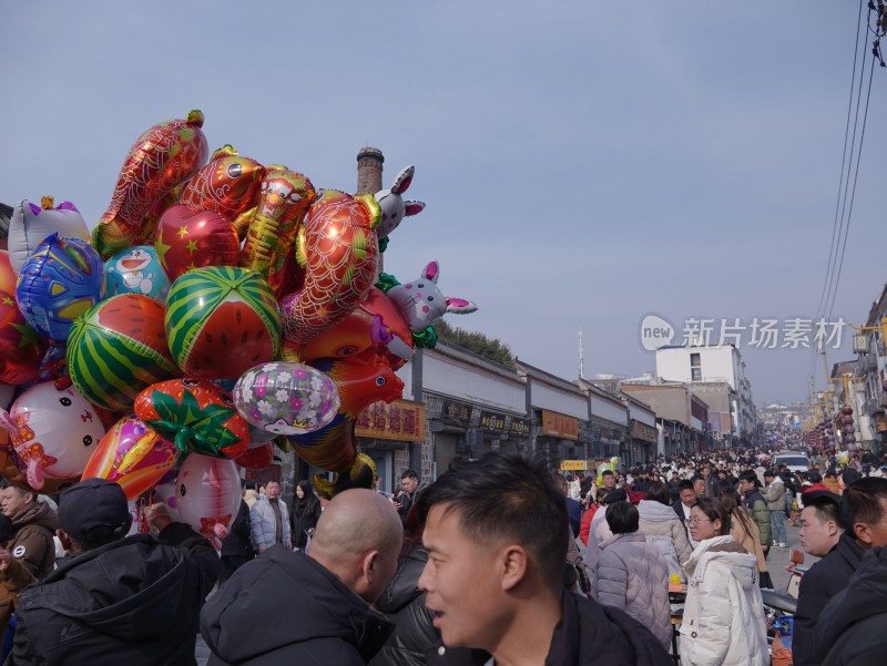 热闹街市上售卖多彩卡通气球的场景