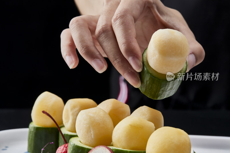 黑色背景上的创意美食手打马铃薯球配乳瓜段