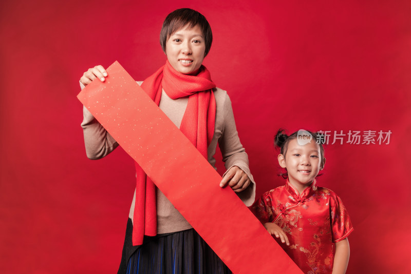 站在红色背景前拿空白春联纸的中国母女