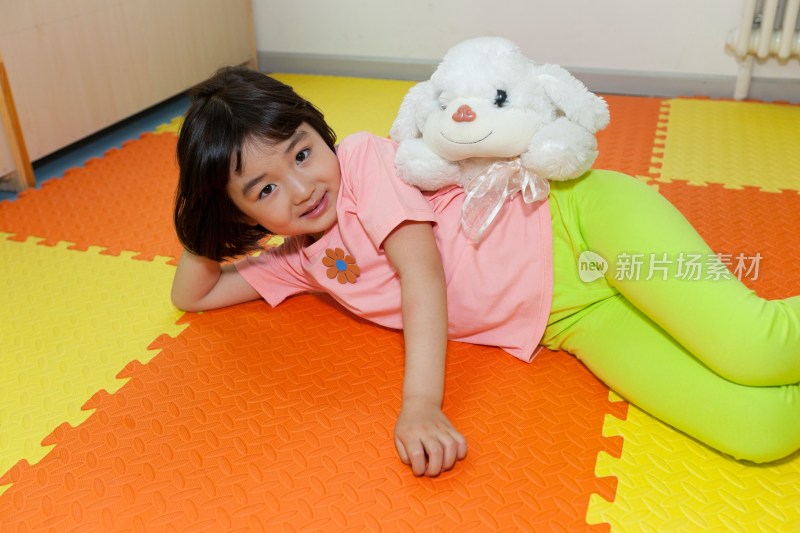 幼儿园小女孩和毛绒玩具躺在地板上玩耍
