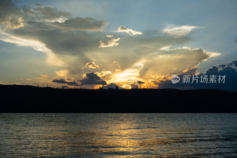 水面上空夕阳透过云层景象