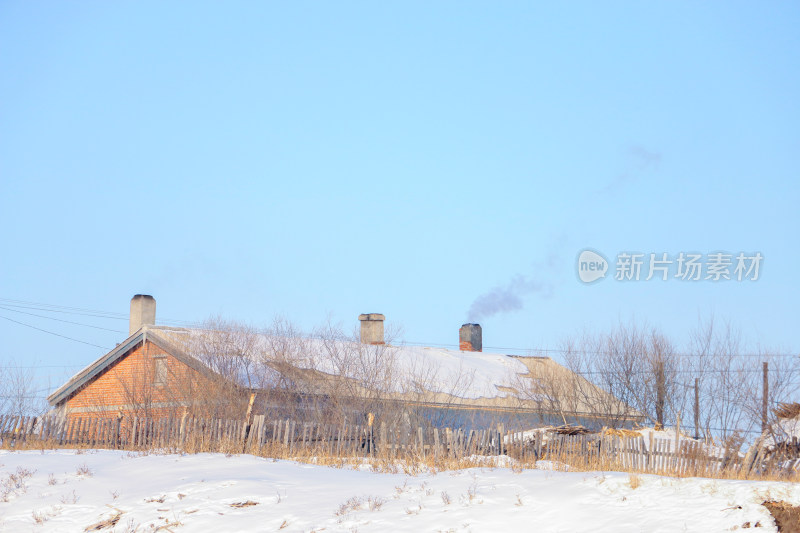 雪后乡村小屋屋顶烟囱冒烟景象