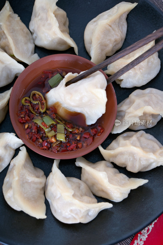 盘子里的饺子蘸进醋和辣椒调制的蘸料中