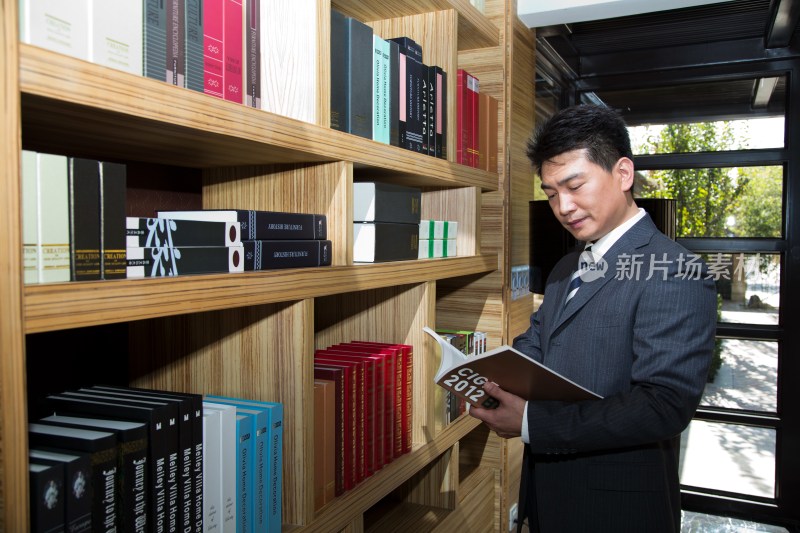 中年商务男士在书柜前看书