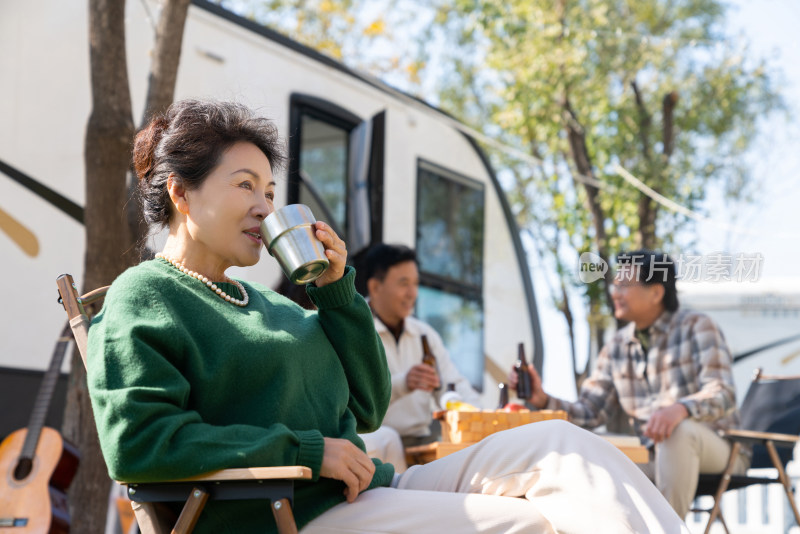 一个老年女人坐在房车露营地喝咖啡