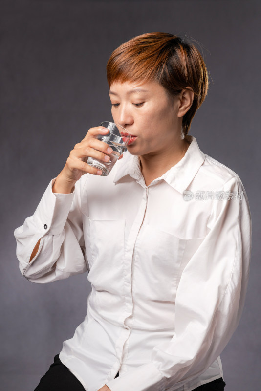 穿白色衬衫喝水的年轻中国女性