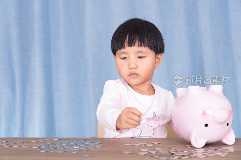 中国小女孩在摆弄着粉色的小猪存钱罐