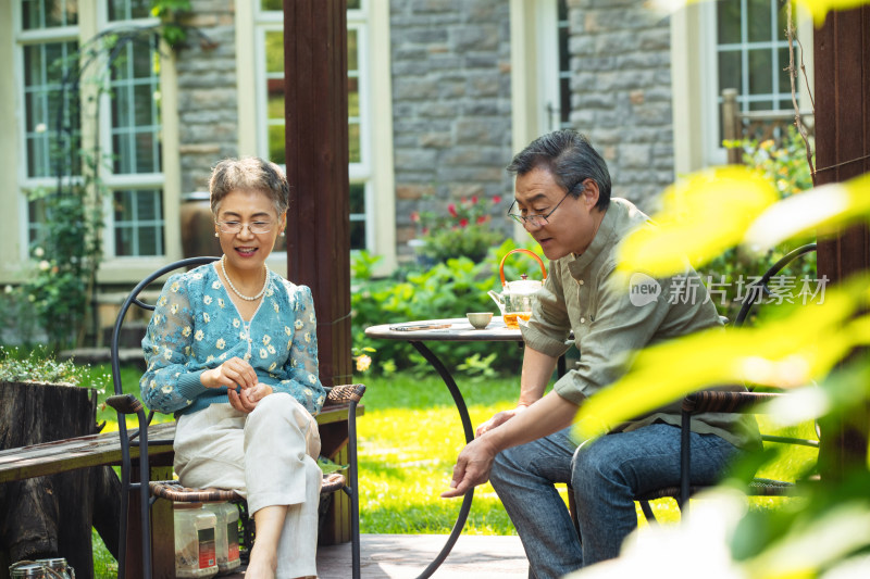 老年夫妇在院子里喝茶喂鱼