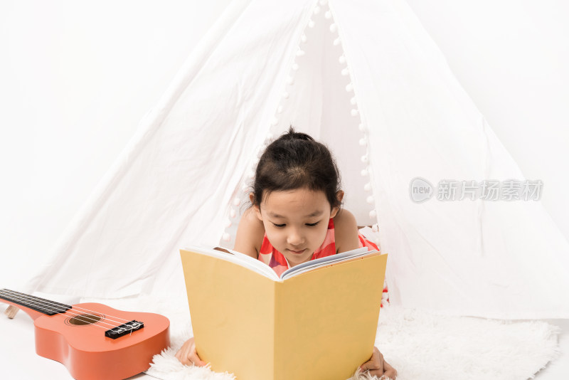 趴在白色帐篷里读书的女孩