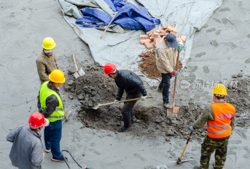 建筑工地上几个合作挖坑的建筑工人