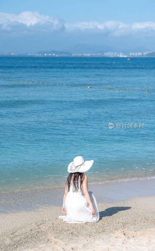 海南三亚漂亮女孩在沙滩拍摄蔚蓝色海洋背影