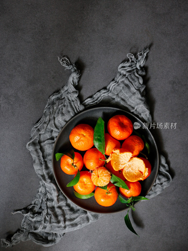 黑色桌面上，一盘子的广西新鲜水果砂糖桔
