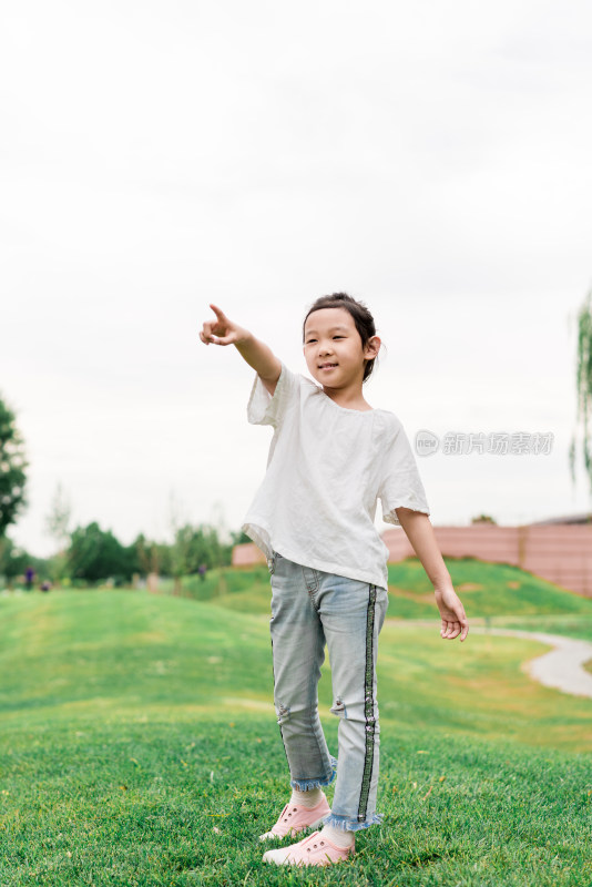 夏天站在草坪上手指向前方的中国女孩