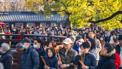 古建前人群手持香烛聚集场面