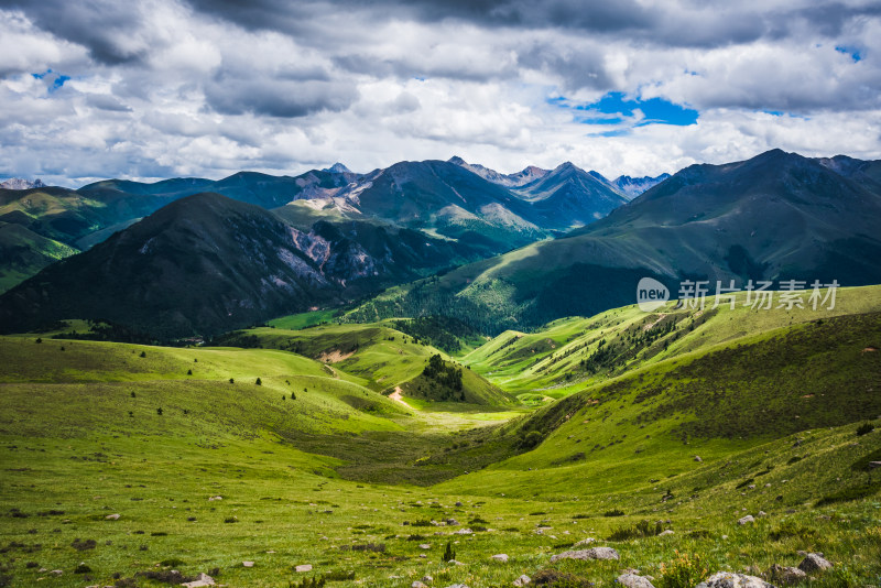 蓝天白云下广袤草原与连绵山峦自然风景