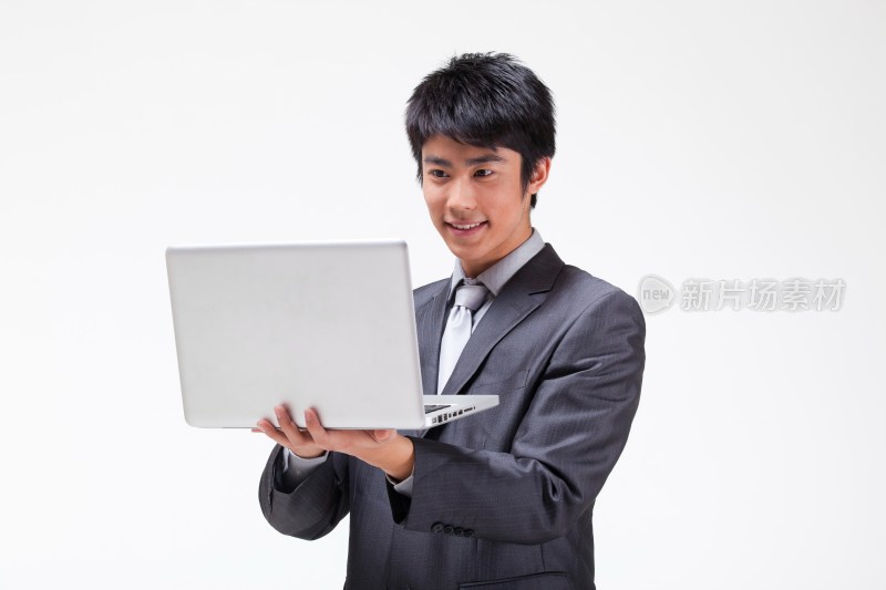 年轻的商务男士抱着笔记本电脑