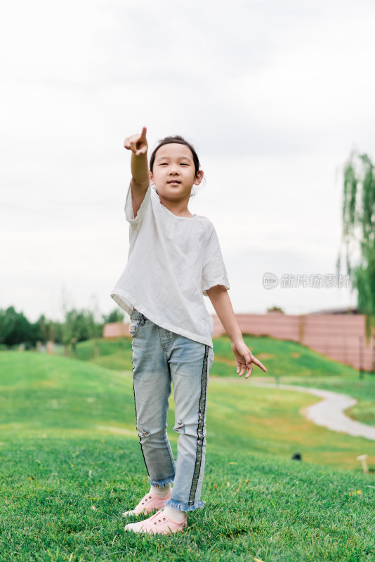 夏天站在草坪上手指向前方的中国女孩