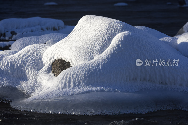 冬日新疆喀纳斯湖面岩石被雪覆盖