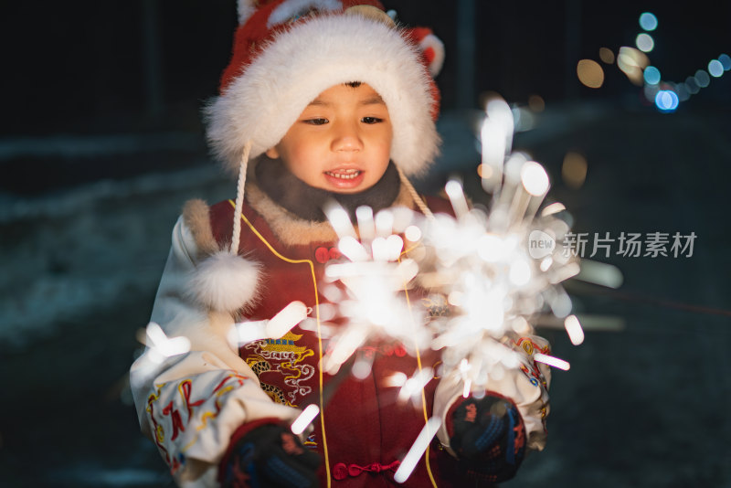 中国农历春节穿传统服饰的小男孩夜晚放烟花